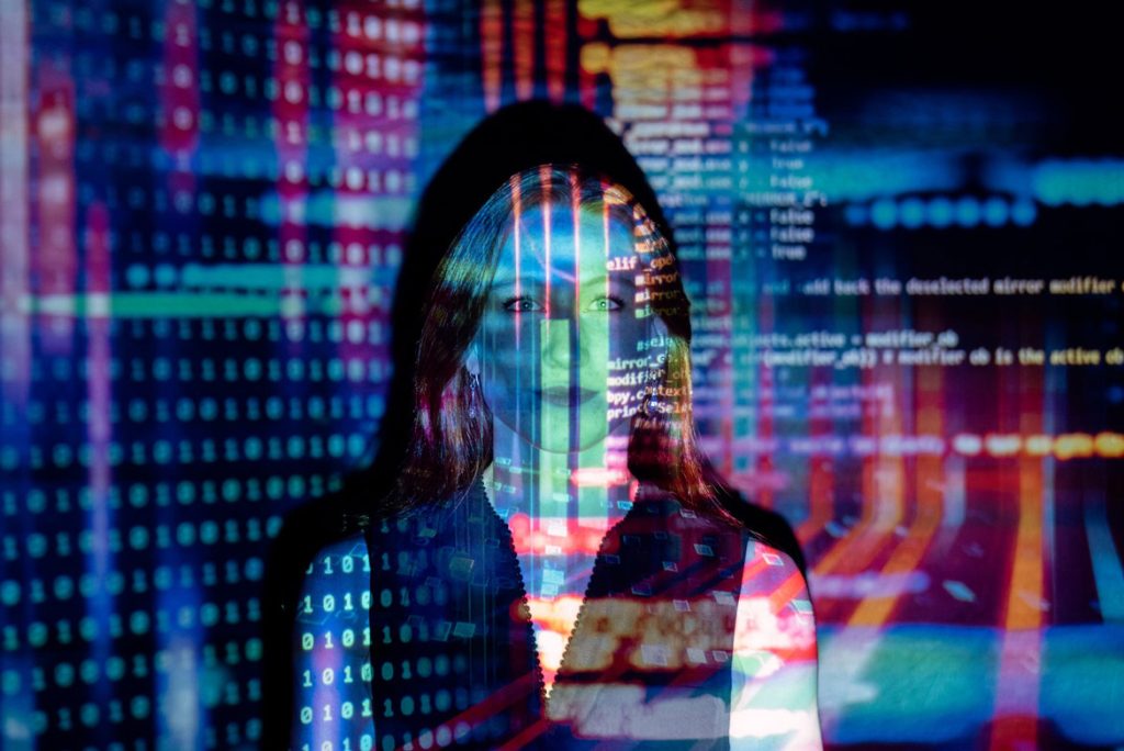 Woman standing within a colorful projection of code.